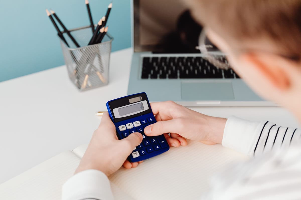 Calcul d'un budget à la calculatrice devant un ordinateur portable