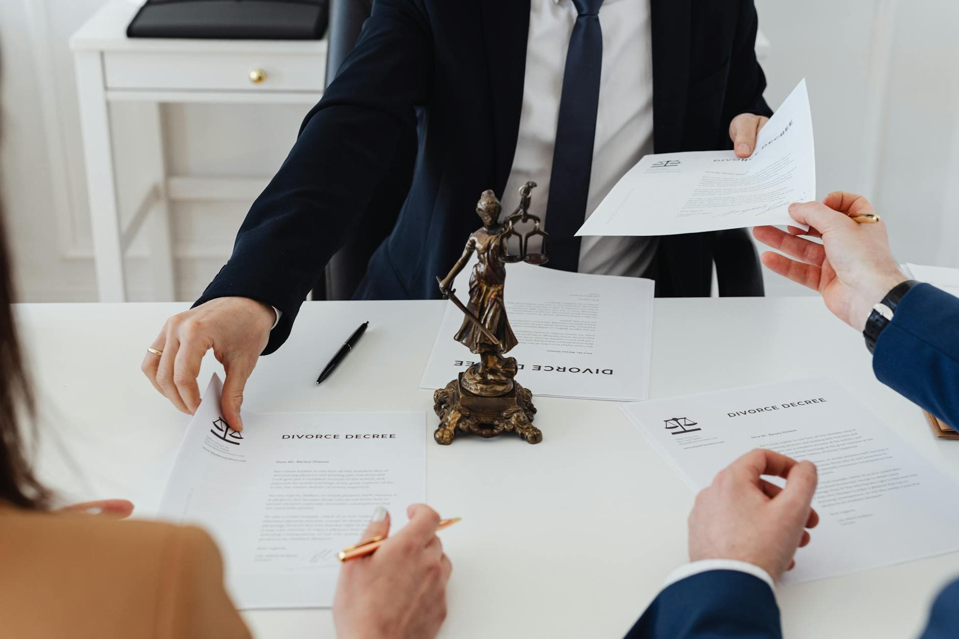 Trois adultes examinent des documents de divorce contentieux dans un cabinet, cadre juridique.