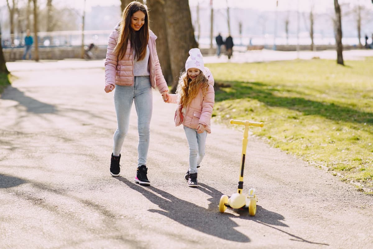 Une mère et sa fille marchent main dans la main dans un parc